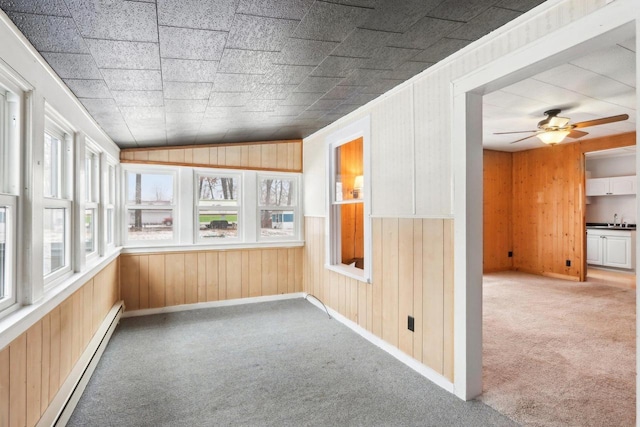 unfurnished sunroom featuring ceiling fan, a baseboard radiator, vaulted ceiling, and a sink