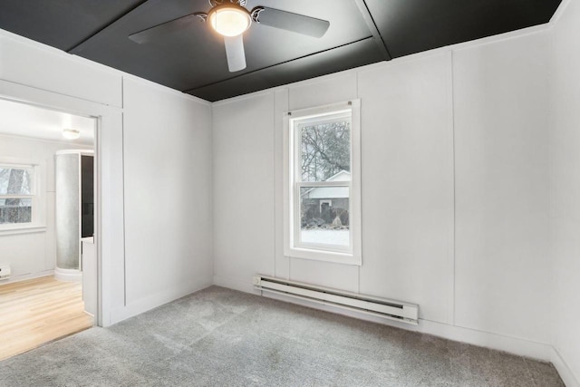 carpeted spare room with a ceiling fan and baseboard heating