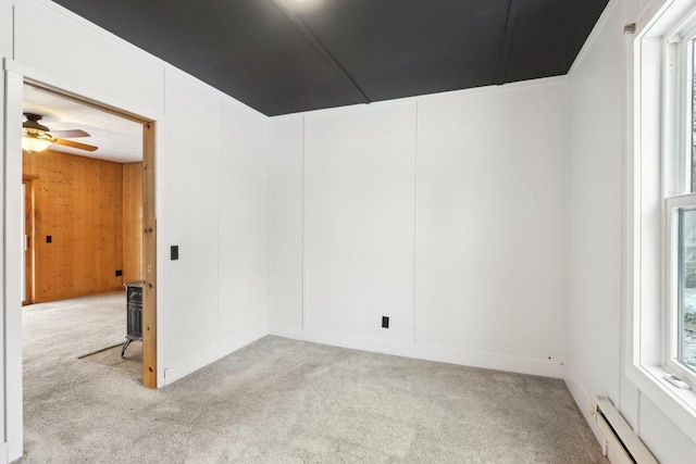 carpeted empty room with a ceiling fan and baseboard heating