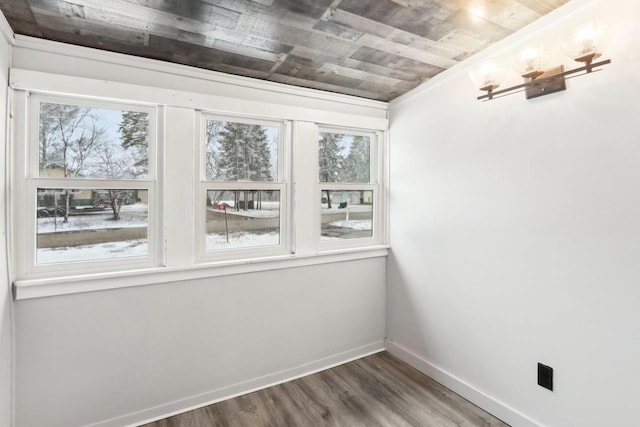 spare room with wood ceiling, plenty of natural light, baseboards, and wood finished floors