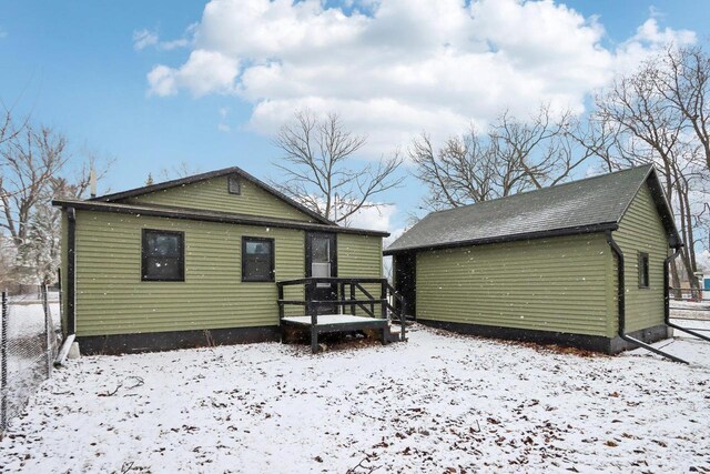 snow covered property with fence and an outdoor structure