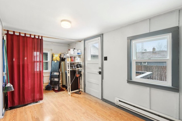 foyer entrance with a baseboard radiator and wood finished floors