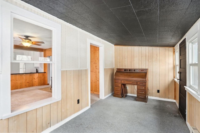 interior space featuring wood walls and a ceiling fan