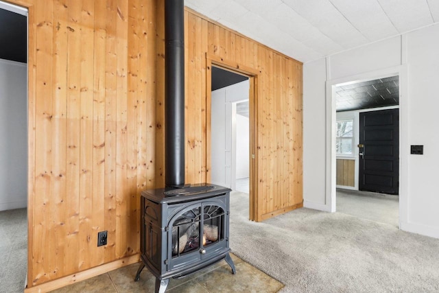 room details with a wood stove, carpet, wooden walls, and baseboards