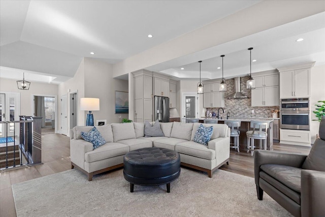 living area with light wood-style floors, recessed lighting, and a raised ceiling