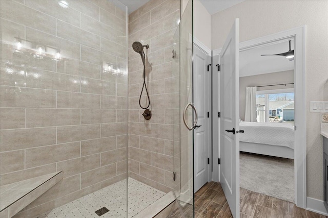 bathroom featuring wood tiled floor, a tile shower, baseboards, and ensuite bathroom