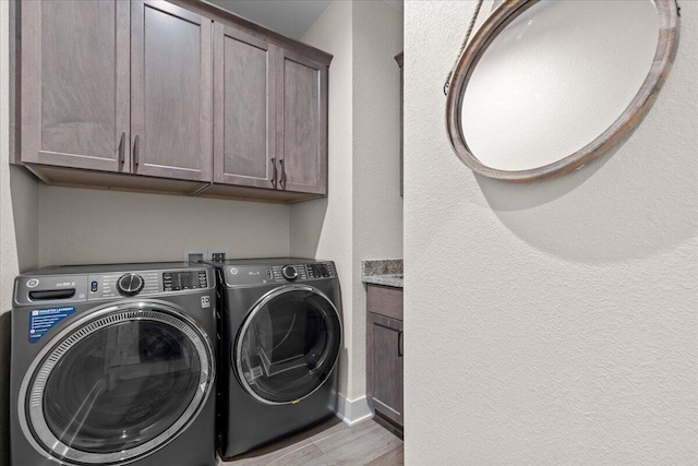 laundry room featuring wood finished floors, cabinet space, and washer and dryer