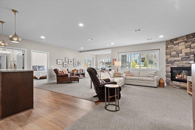 living area featuring a stone fireplace, recessed lighting, visible vents, and light wood-style floors