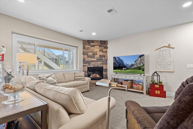 living room with a textured ceiling, carpet floors, a fireplace, and visible vents