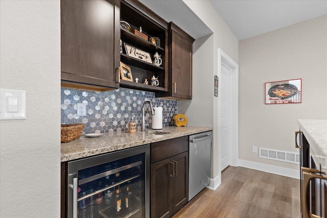 bar with beverage cooler, tasteful backsplash, visible vents, dishwasher, and indoor wet bar