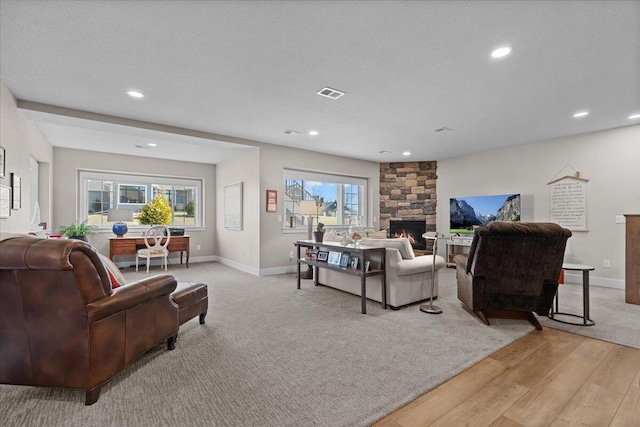 living room with a fireplace, visible vents, and a textured ceiling