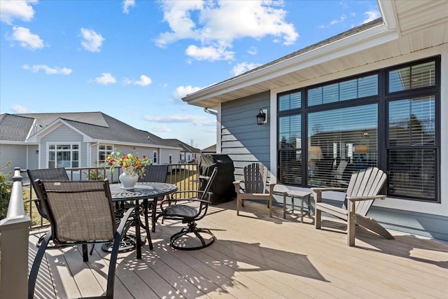 wooden terrace with outdoor dining area and grilling area