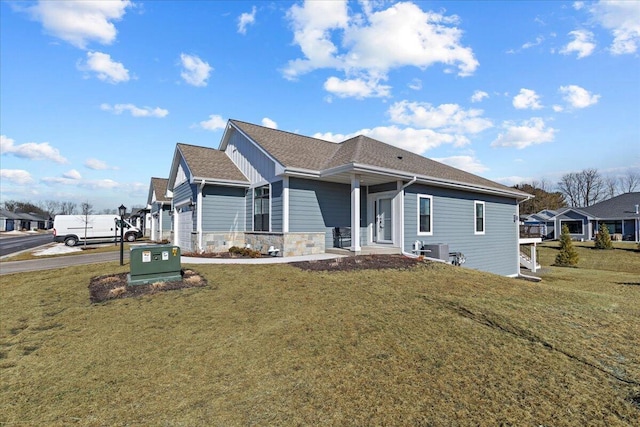 view of front of home featuring cooling unit, stone siding, an attached garage, and a front lawn