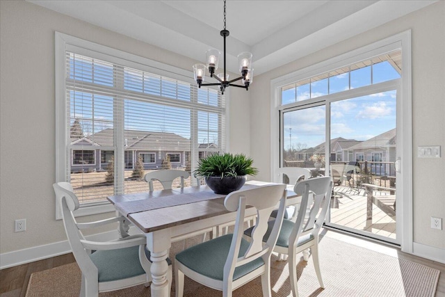 dining room with a wealth of natural light, an inviting chandelier, and wood finished floors