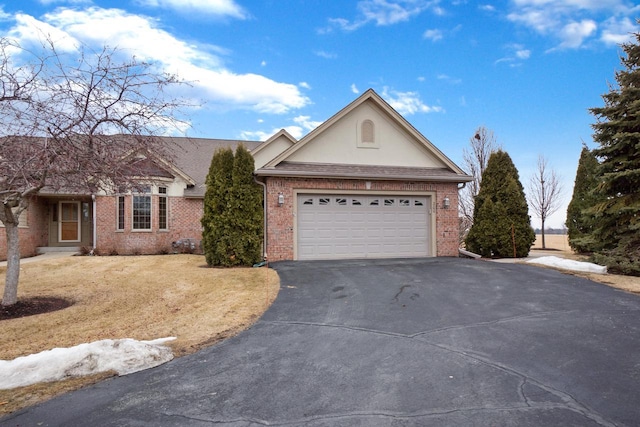 single story home with driveway, an attached garage, a front yard, and brick siding