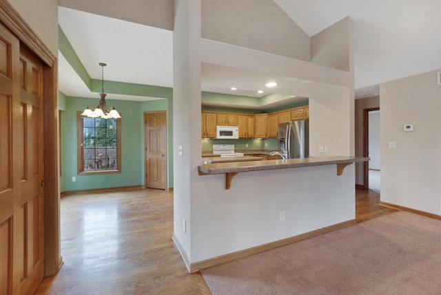 kitchen with white microwave, stove, stainless steel refrigerator with ice dispenser, and a breakfast bar area