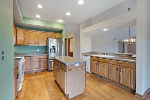 kitchen featuring recessed lighting, light wood-style floors, a sink, a kitchen island, and white appliances