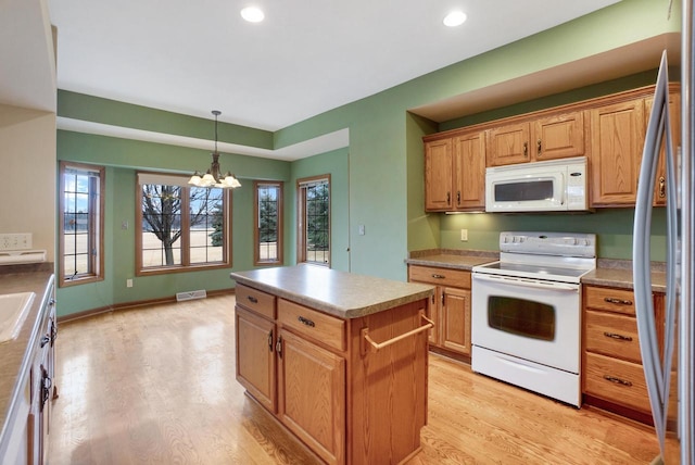 kitchen featuring a notable chandelier, white appliances, a kitchen island, baseboards, and light wood finished floors