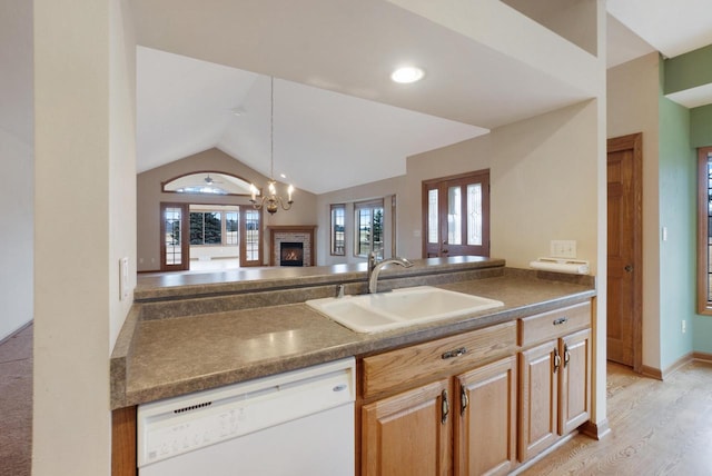 kitchen featuring white dishwasher, a sink, light wood-style floors, vaulted ceiling, and dark countertops