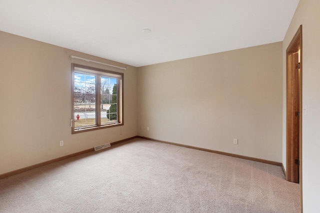 unfurnished room with light carpet, visible vents, and baseboards