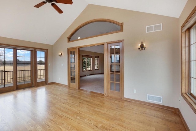 unfurnished room with light wood-type flooring, high vaulted ceiling, visible vents, and french doors