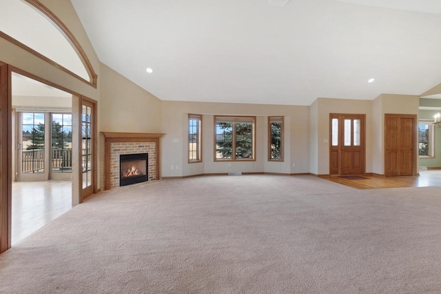 unfurnished living room with high vaulted ceiling, recessed lighting, light colored carpet, a fireplace, and baseboards