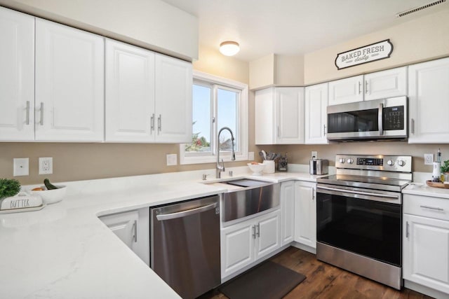 kitchen featuring visible vents, appliances with stainless steel finishes, light countertops, white cabinetry, and a sink