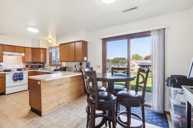 kitchen featuring a peninsula, visible vents, light countertops, light floors, and white range with electric cooktop