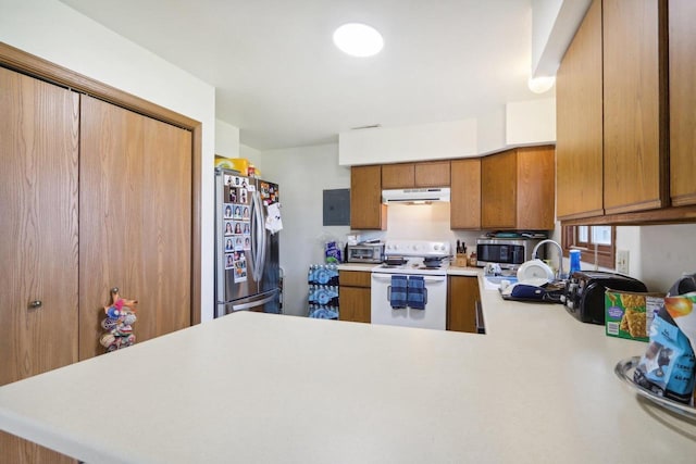 kitchen with light countertops, appliances with stainless steel finishes, brown cabinetry, a peninsula, and under cabinet range hood