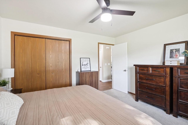 bedroom featuring ceiling fan, a closet, and light colored carpet