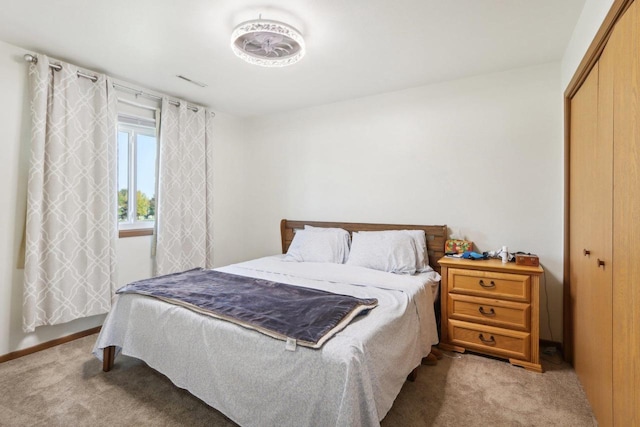 bedroom with a closet, light colored carpet, and visible vents