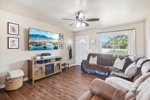 living room with a ceiling fan, baseboards, and wood finished floors