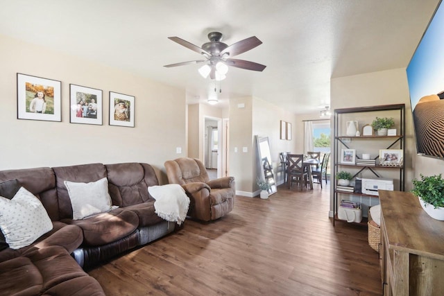 living area featuring ceiling fan, baseboards, and dark wood finished floors