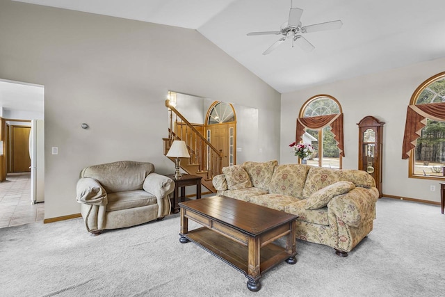 living area with stairs, high vaulted ceiling, baseboards, and light colored carpet