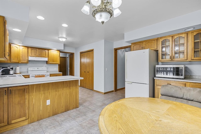 kitchen featuring under cabinet range hood, white appliances, a sink, light countertops, and glass insert cabinets