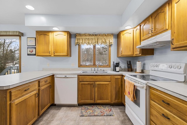 kitchen with under cabinet range hood, a peninsula, white appliances, a sink, and light countertops