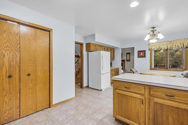 kitchen featuring brown cabinets, a chandelier, light countertops, and freestanding refrigerator