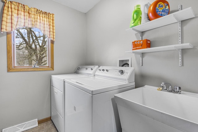 washroom with laundry area, a sink, visible vents, baseboards, and washer and clothes dryer