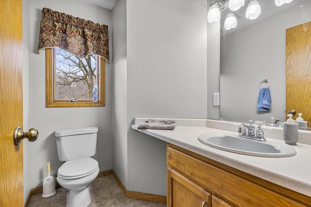 half bath with vanity, tile patterned flooring, toilet, and baseboards