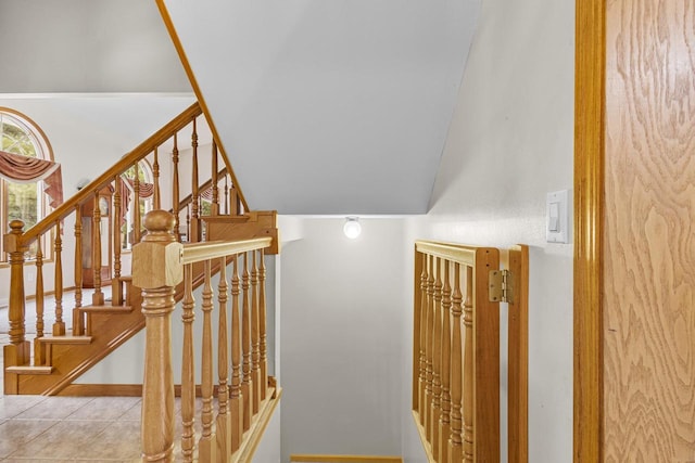 stairway featuring lofted ceiling and tile patterned flooring