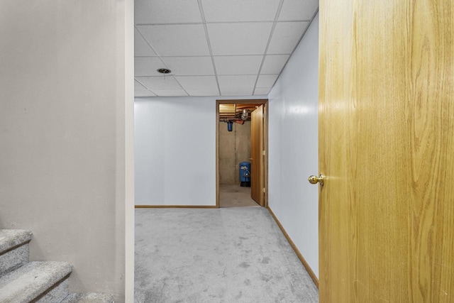 corridor featuring stairs, carpet floors, a drop ceiling, and baseboards