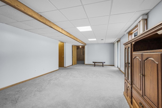 finished basement featuring light carpet, baseboards, and a drop ceiling