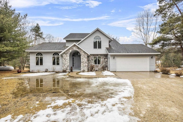 view of front of house featuring a garage, stone siding, roof with shingles, and driveway