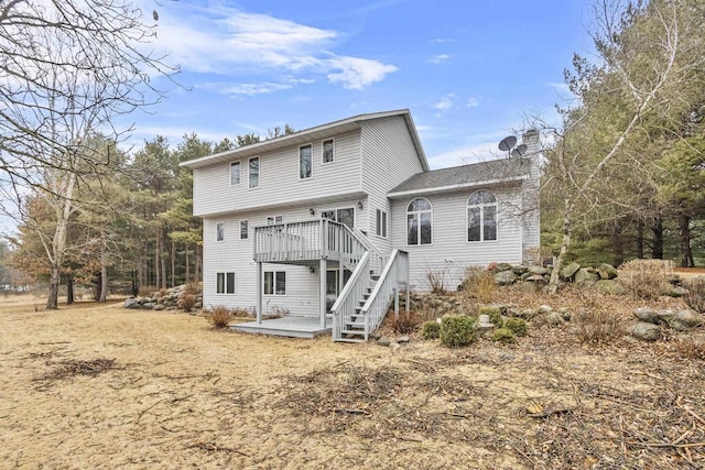 rear view of house with stairway, a chimney, and a wooden deck