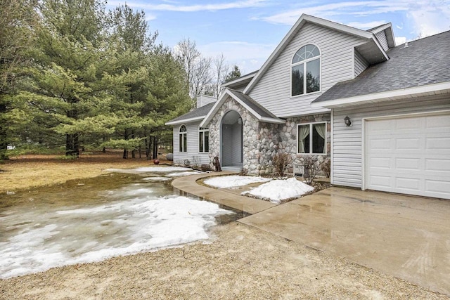 view of front of property with roof with shingles, a chimney, a garage, stone siding, and driveway