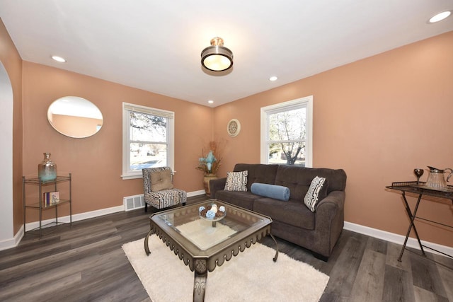 living area with baseboards, plenty of natural light, visible vents, and wood finished floors