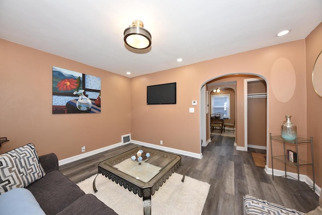 living area with arched walkways, baseboards, and wood finished floors