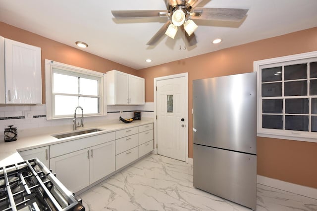 kitchen with freestanding refrigerator, marble finish floor, a sink, and recessed lighting