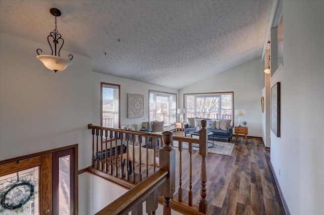 hallway with wood finished floors, an upstairs landing, lofted ceiling, and a textured ceiling