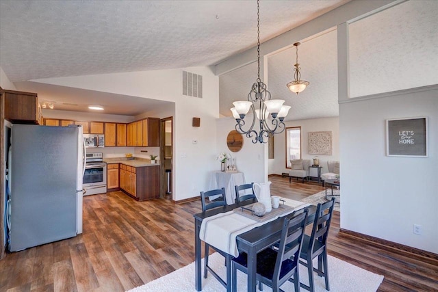 dining space with visible vents, lofted ceiling, dark wood-style flooring, a textured ceiling, and a notable chandelier